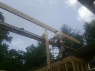 Carpenter setting a ridge beam over a new addition frame — Ice Dam Removal by Roofing Brothers in New Hartford
